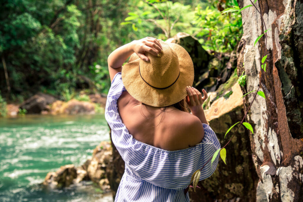 Beautiful young girl in hat at the river in the rainforest ,travel concept