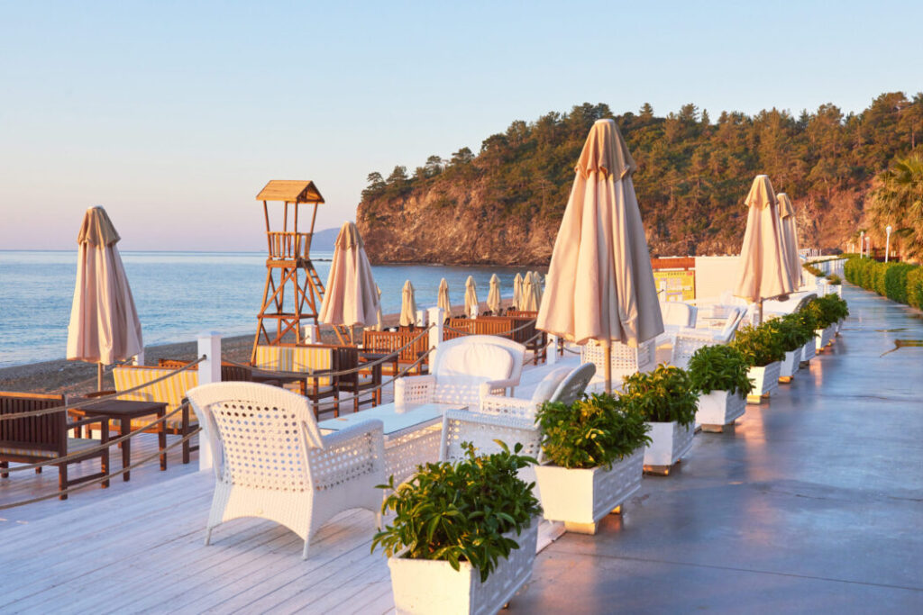 Scenic view of private sandy beach with sun beds and parasokamy the sea and mountains. Resort